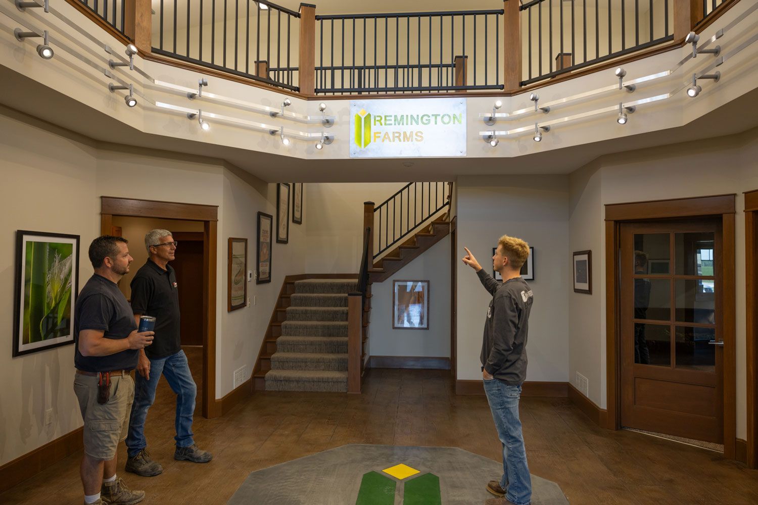 A group of men are standing in a large room with stairs.