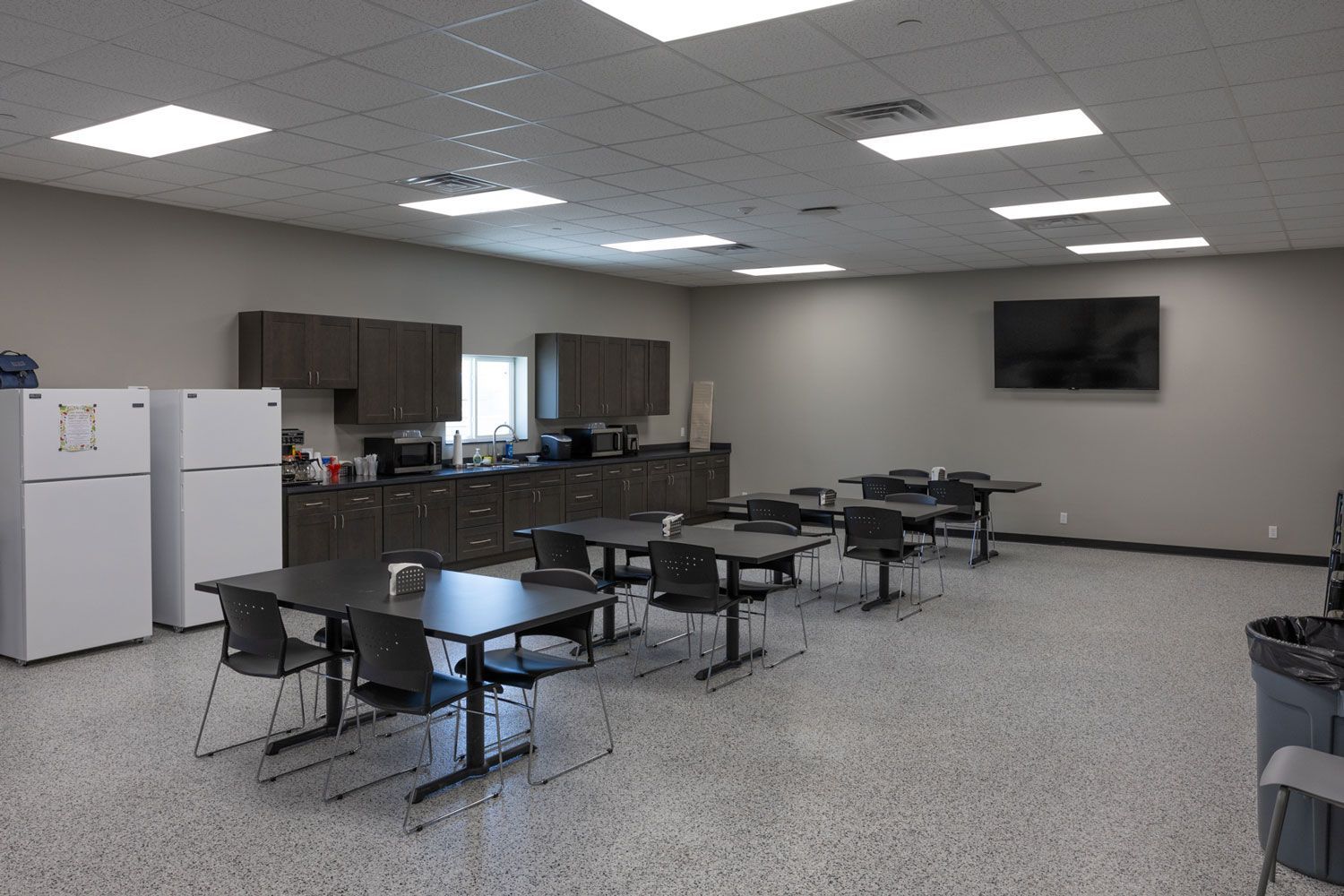 A large room with tables and chairs and two refrigerators