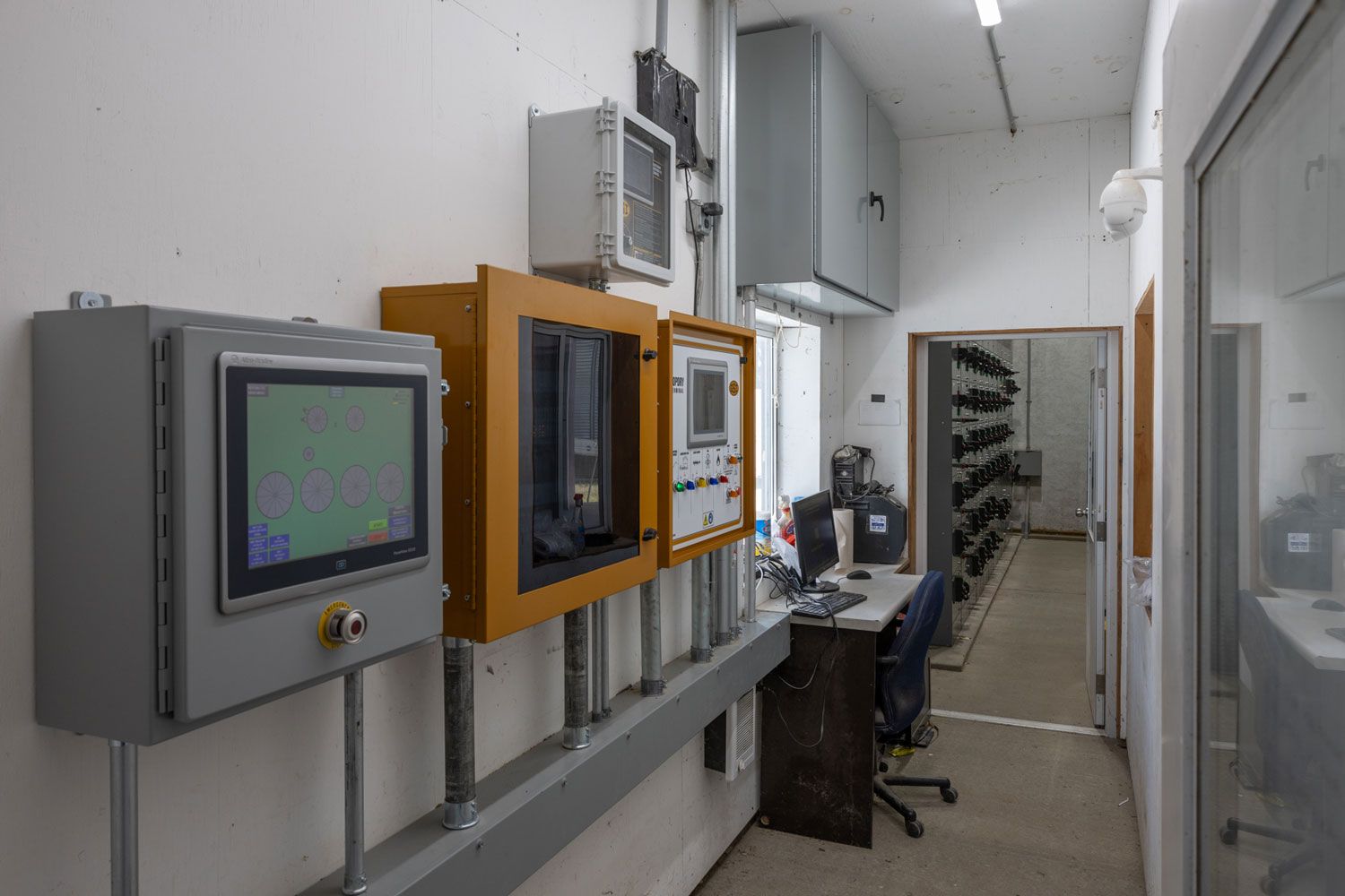 A room with a lot of electrical equipment on the wall and a desk.