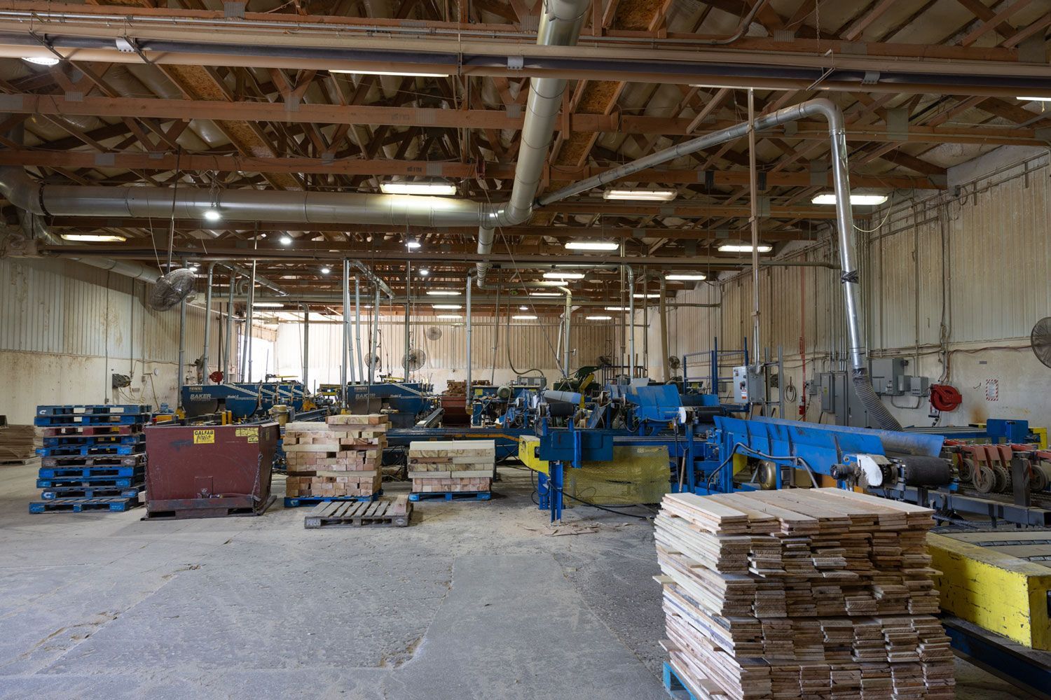 A large warehouse filled with wooden pallets and machinery.