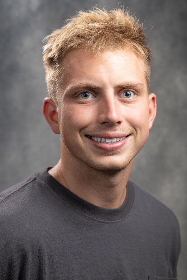 A young man wearing a black shirt is smiling for the camera.
