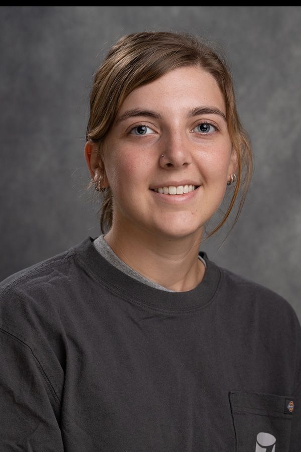A young woman wearing a gray sweatshirt is smiling for the camera.