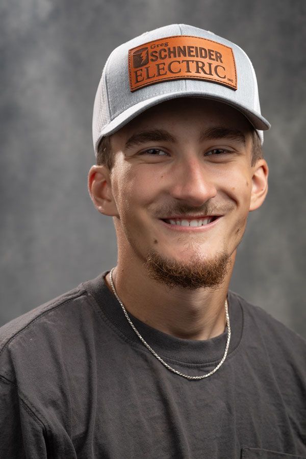 A young man wearing a schneider electric hat is smiling for the camera.