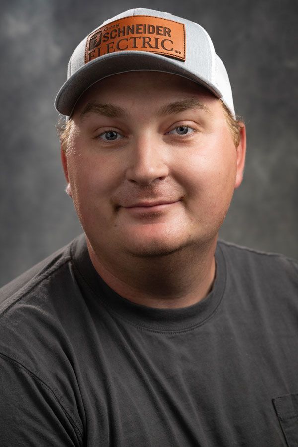 A man wearing a baseball cap and a gray shirt is smiling for the camera.
