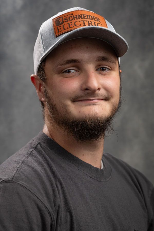 A man with a beard is wearing a baseball cap and a black shirt.