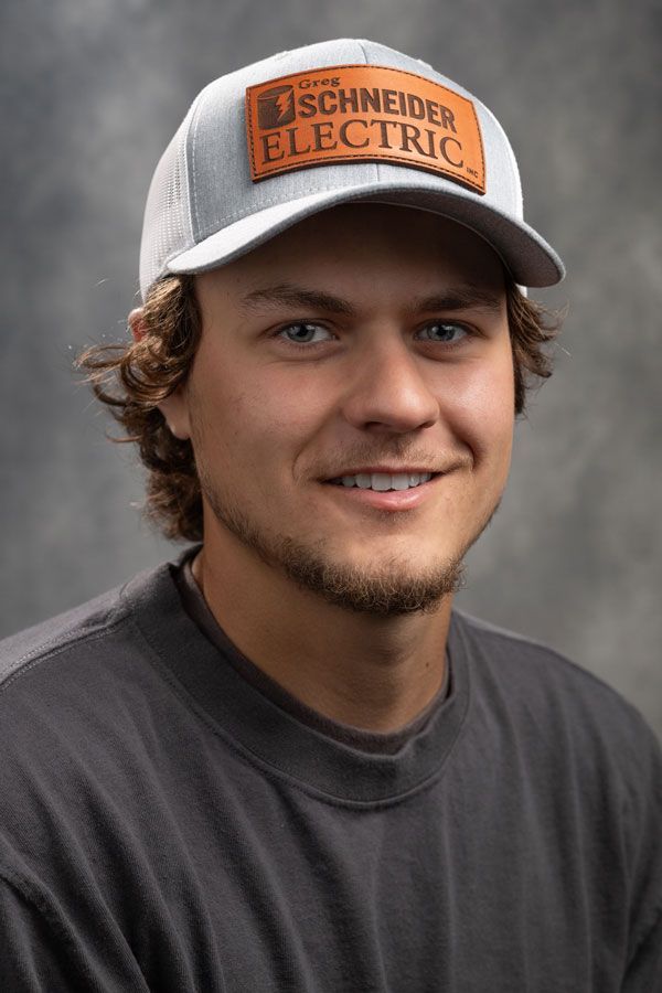A young man wearing a baseball cap and a black shirt is smiling for the camera.