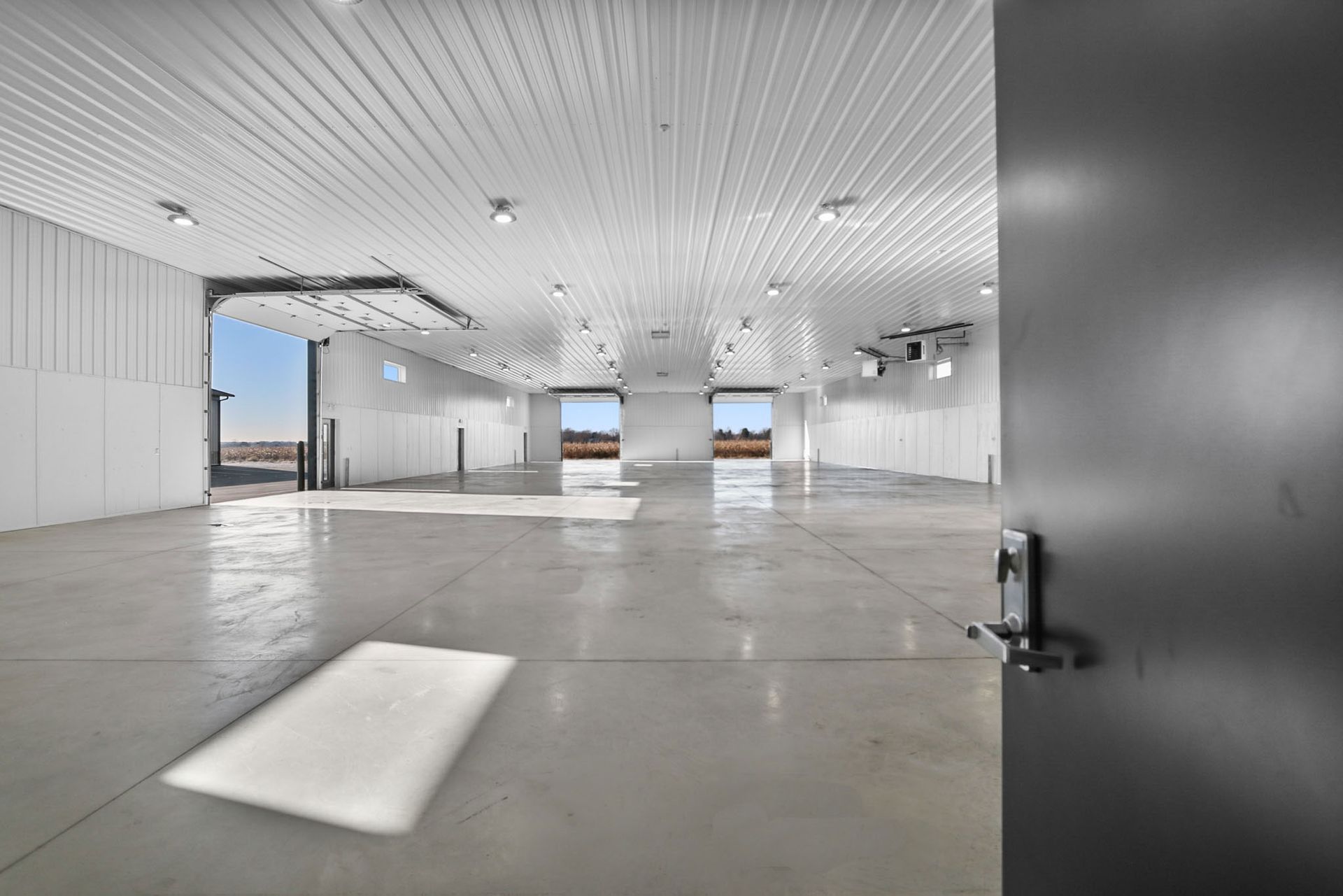 A large empty warehouse with a door open and a piece of paper on the floor.