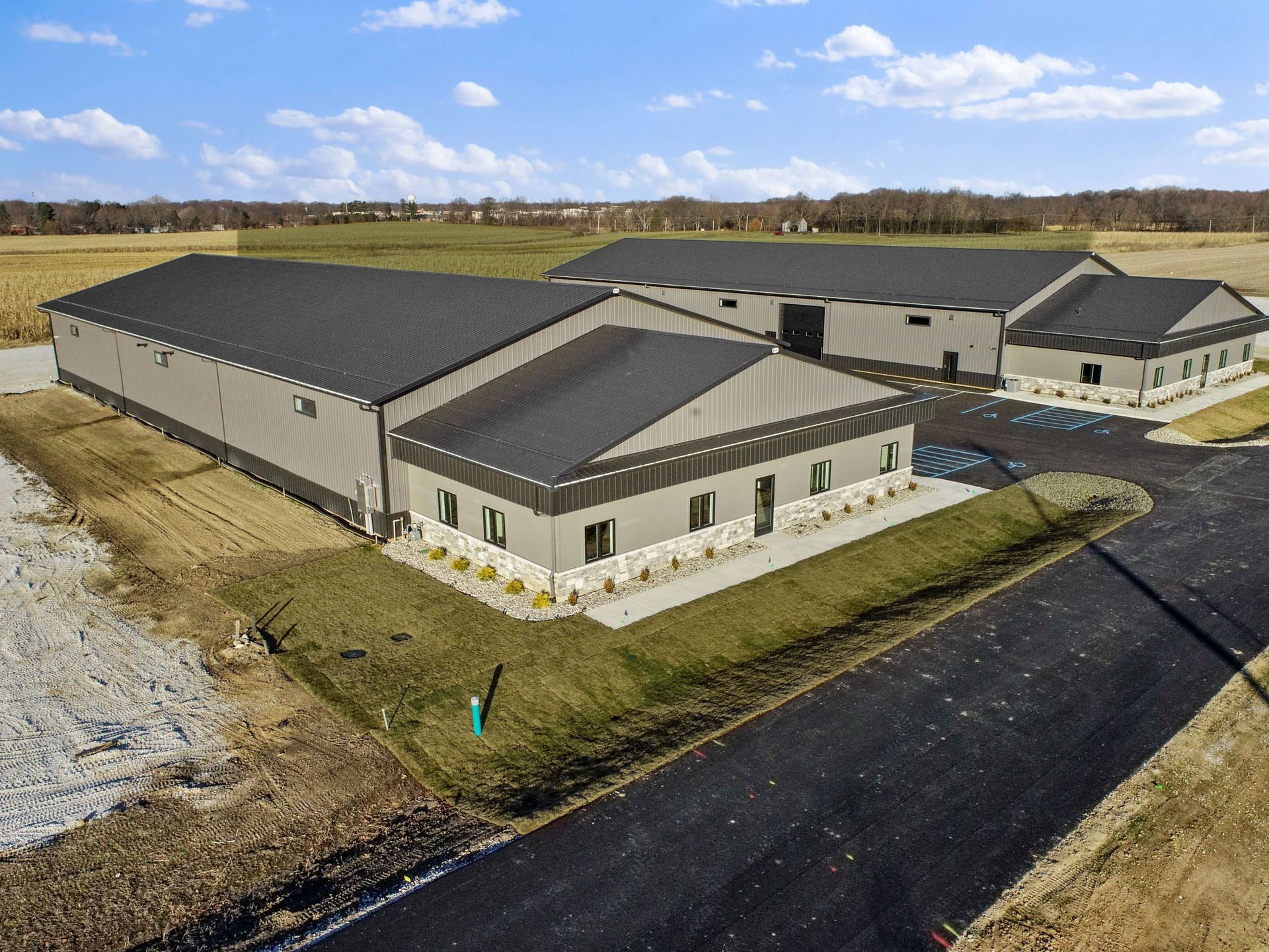 An aerial view of a large building with a black roof in a field.