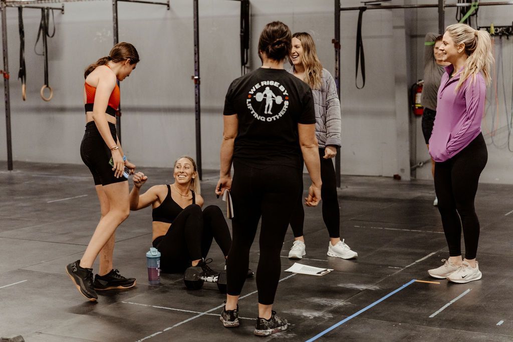 Group of women in the gym in Spanish Fork, UT, chatting. One is sitting. Others stand and laugh.