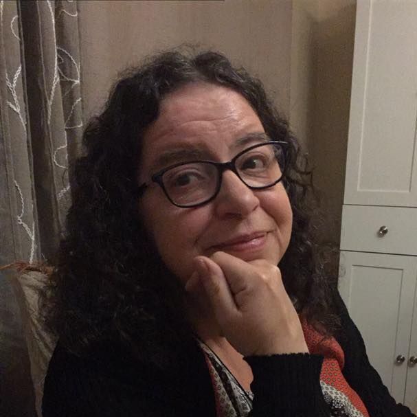 A woman wearing glasses is sitting in a chair with her hand on her chin