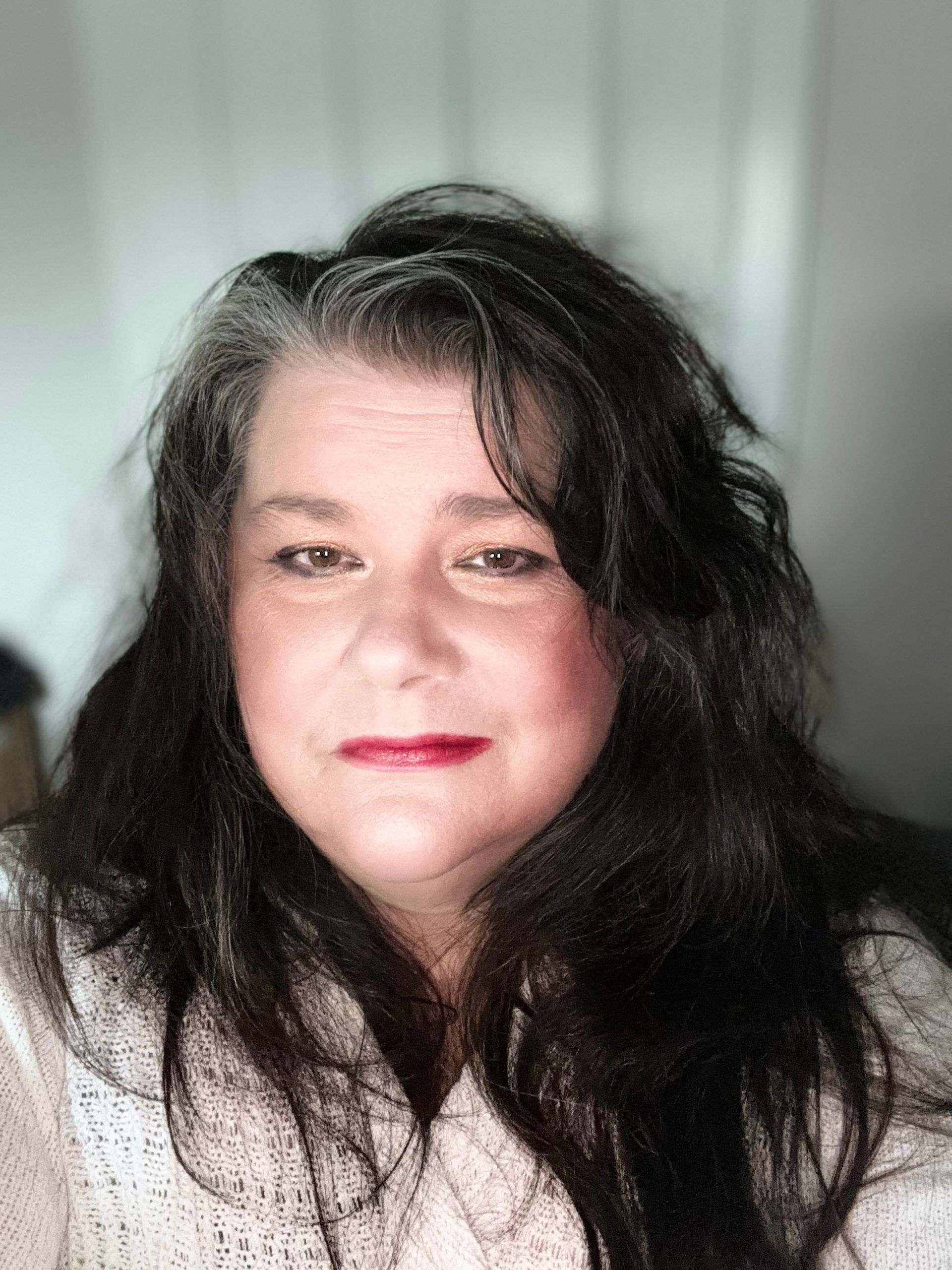 A woman is smiling in front of a floral background