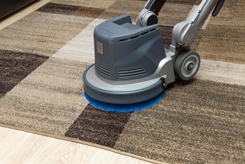 A Machine Is Cleaning A Rug On A Wooden Floor — Mr Steam Clean Tweed Coast In Banora Point, NSW