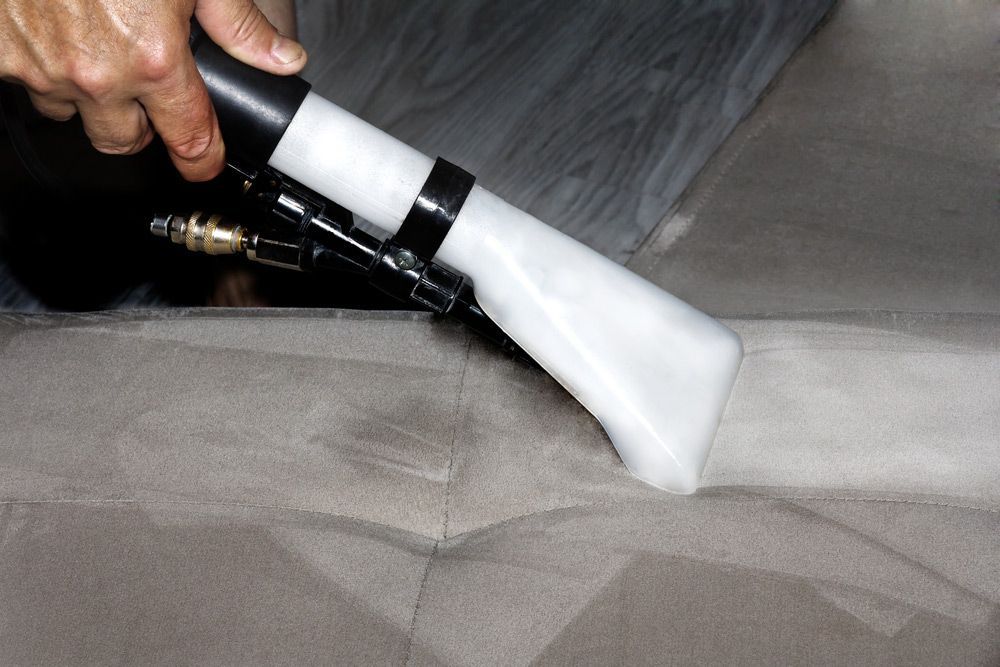 A Person Is Cleaning A Couch With A Vacuum Cleaner — Mr Steam Clean Tweed Coast In Tweed Heads, NSW