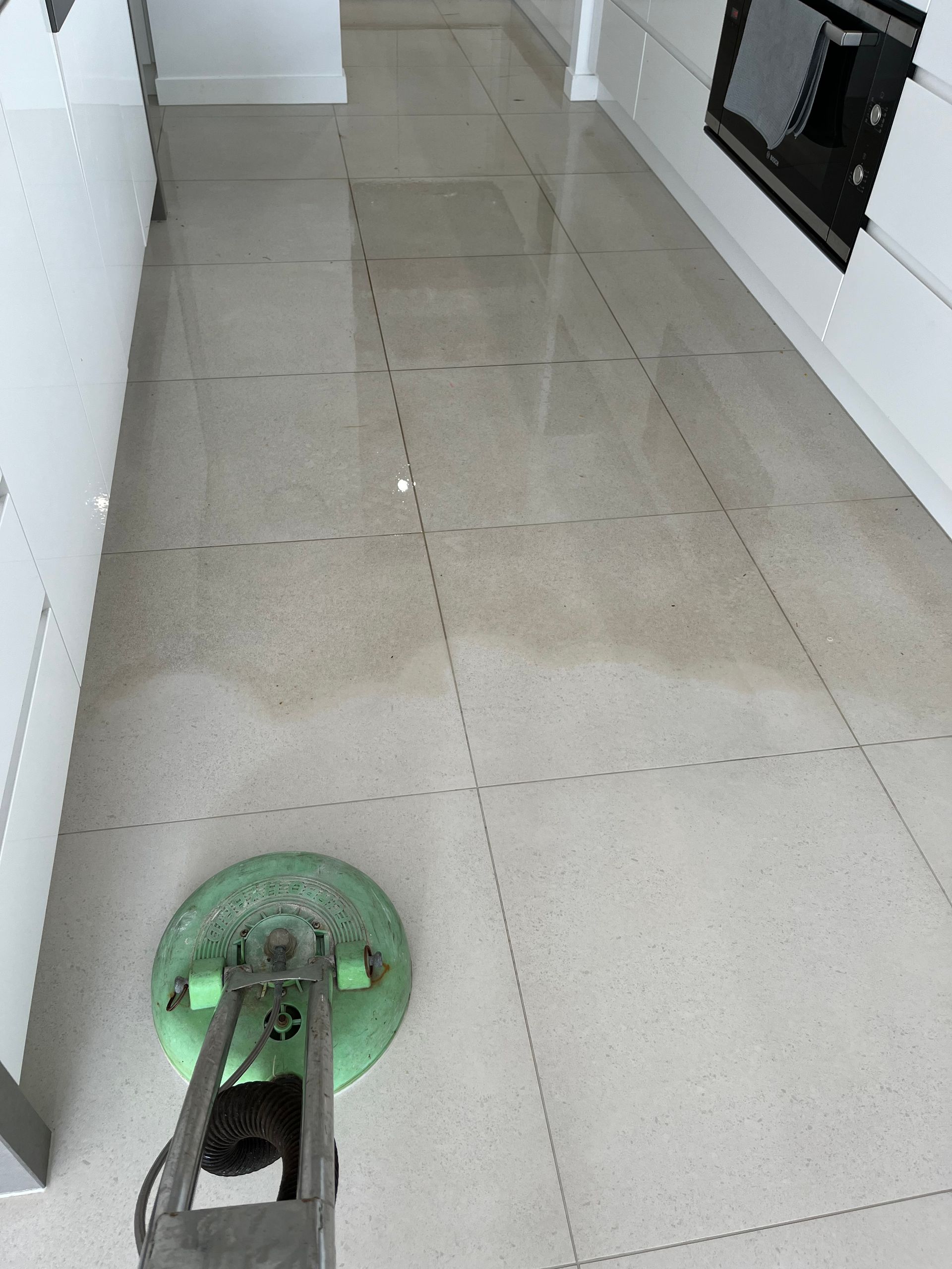 A Green Mop Is Sitting On A Tiled Floor In A Kitche — Mr Steam Clean Tweed Coast In Banora Point, NSW