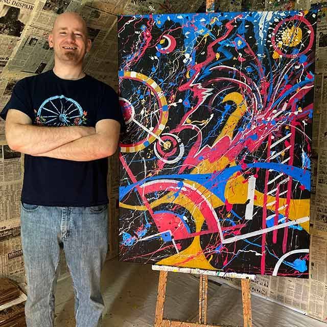 Ryan Conway standing in front of one of his paintings
