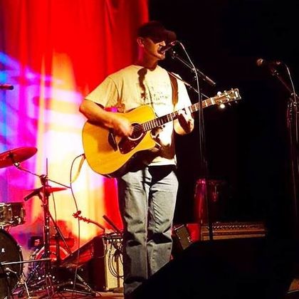 Ryan Conway onstage playing a guitar and singing into a microphone. 