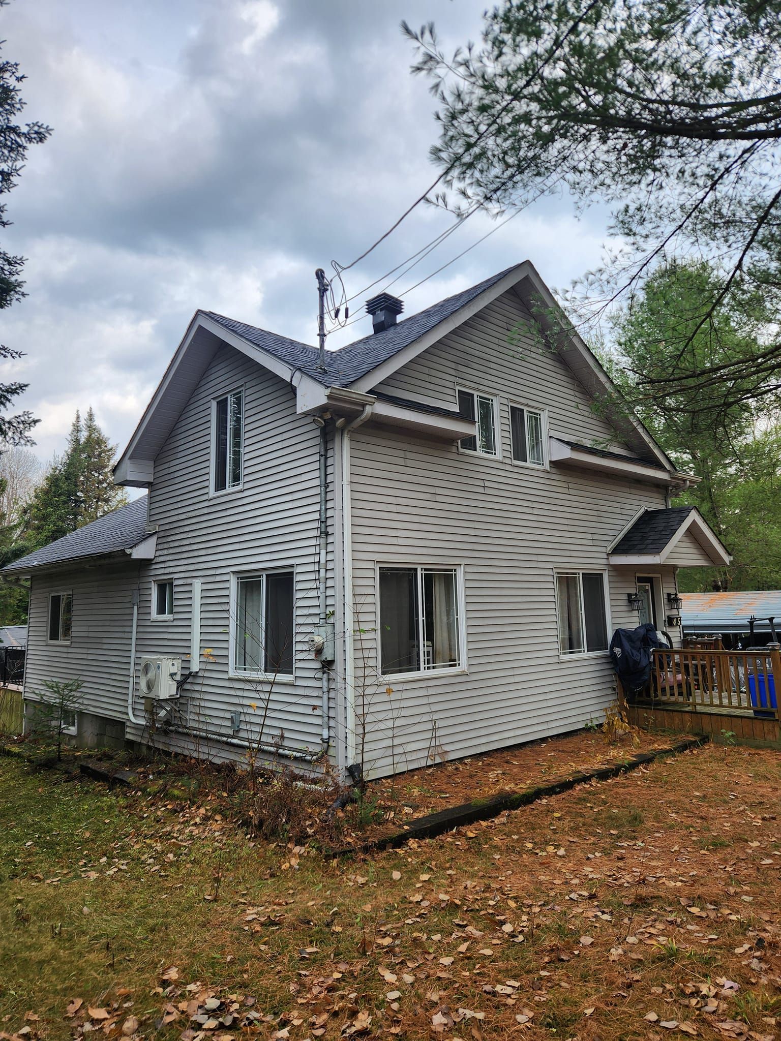 Maison à deux étages avec un revêtement extérieur gris, des encadrements de fenêtres blancs.