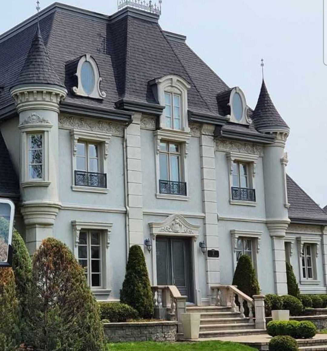 Élégante demeure bleu clair avec tourelles, toit gris et jardins soignés.