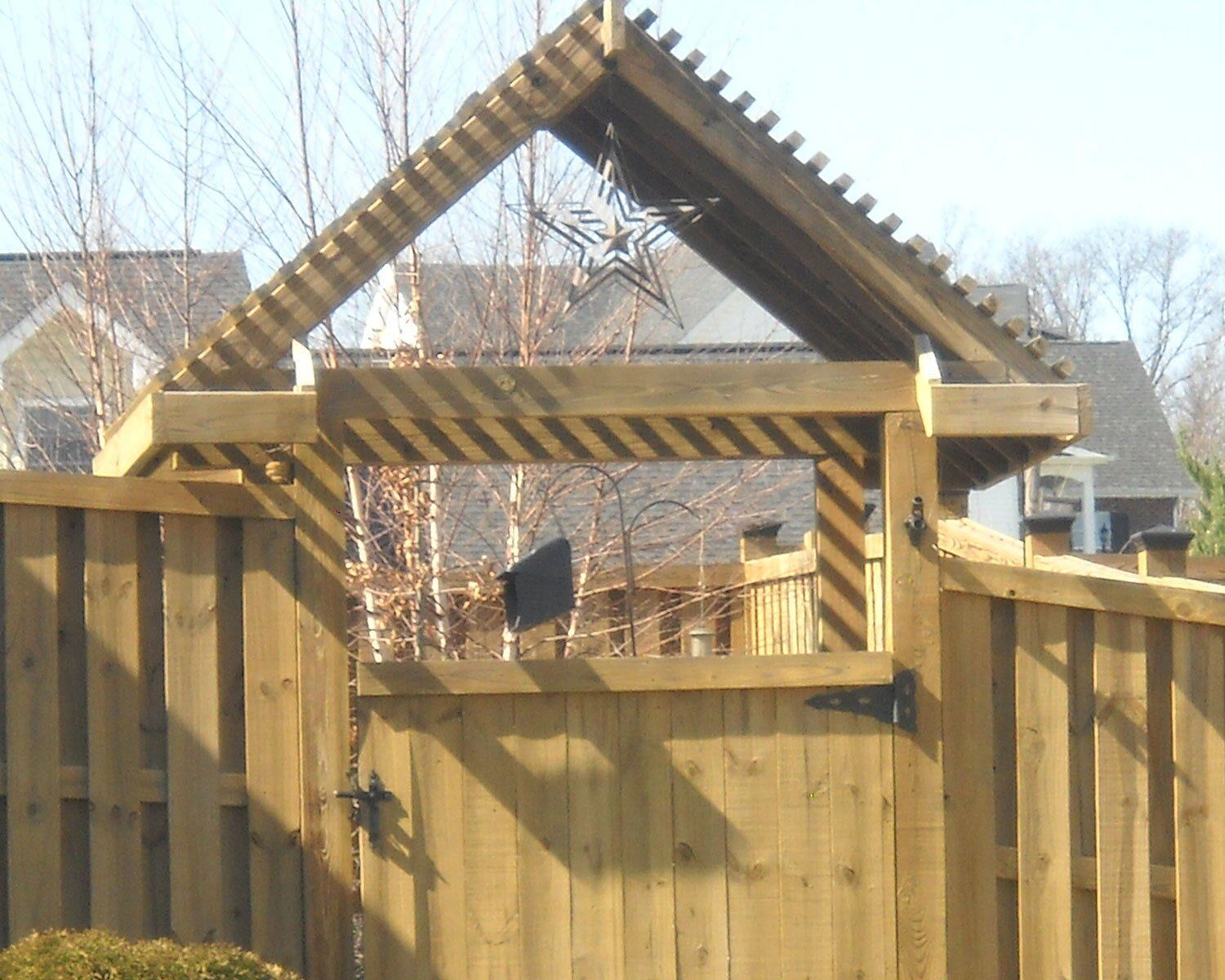 A wooden fence with a pergola on top of it