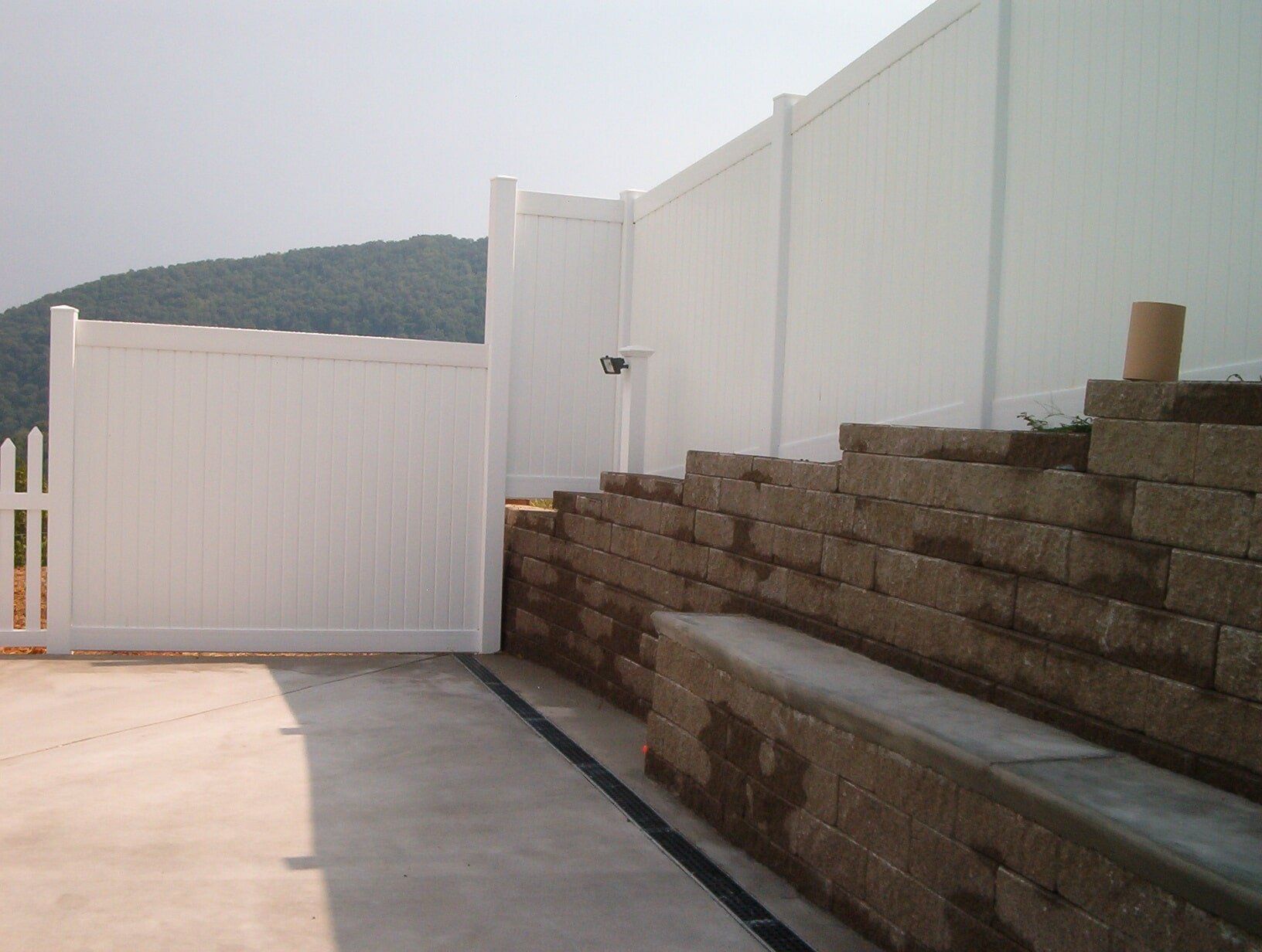 A white fence is surrounded by a brick wall