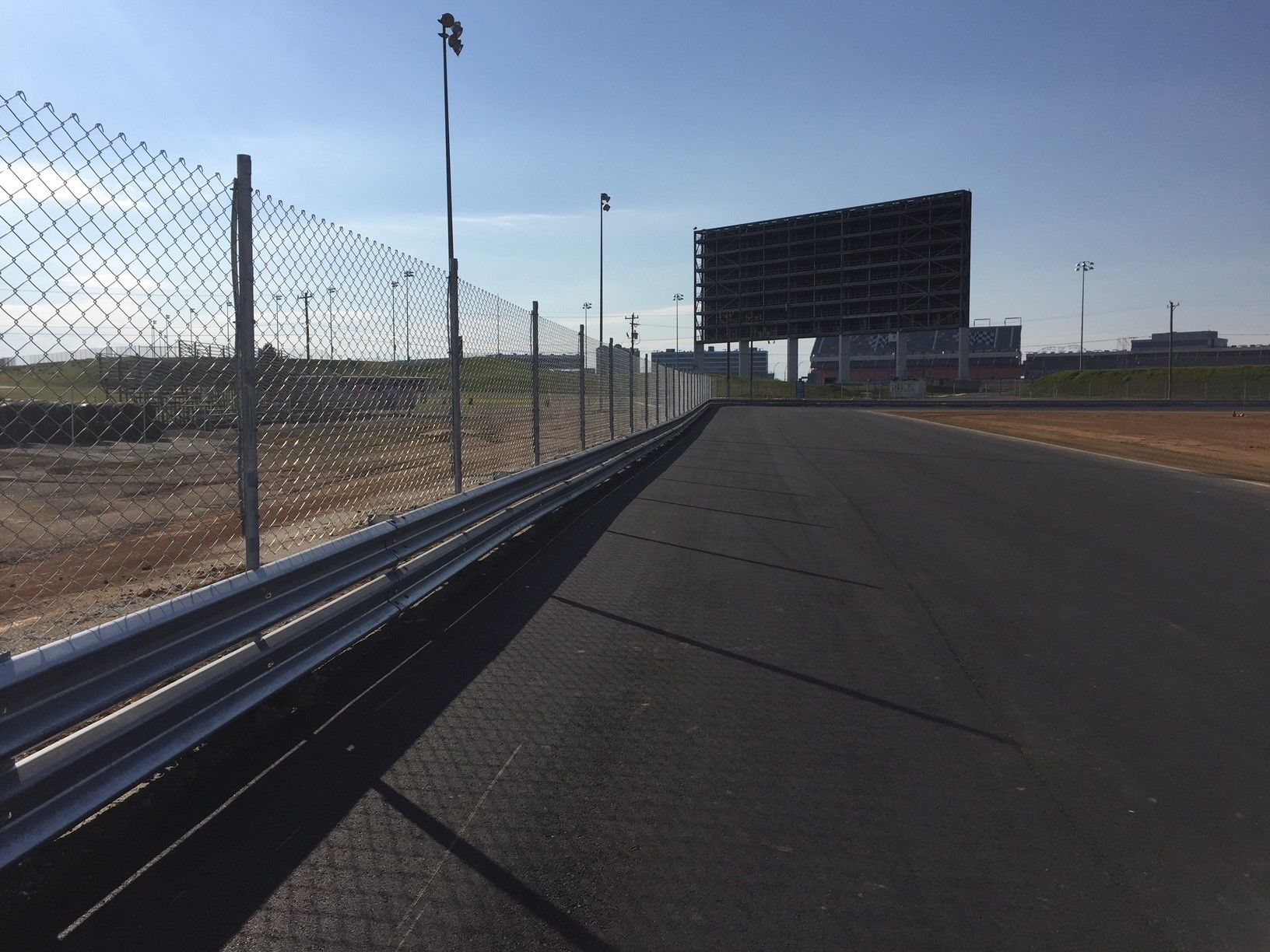 A race track with a fence and a scoreboard in the background