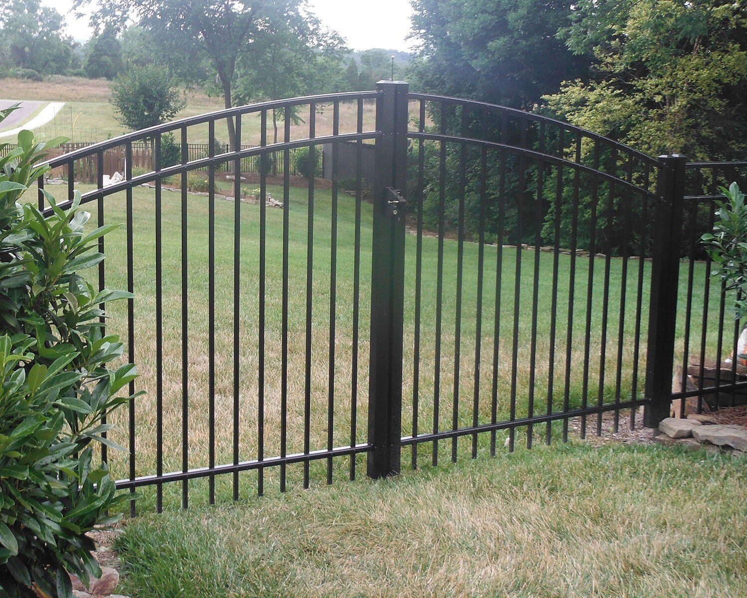 A black metal fence surrounds a lush green field