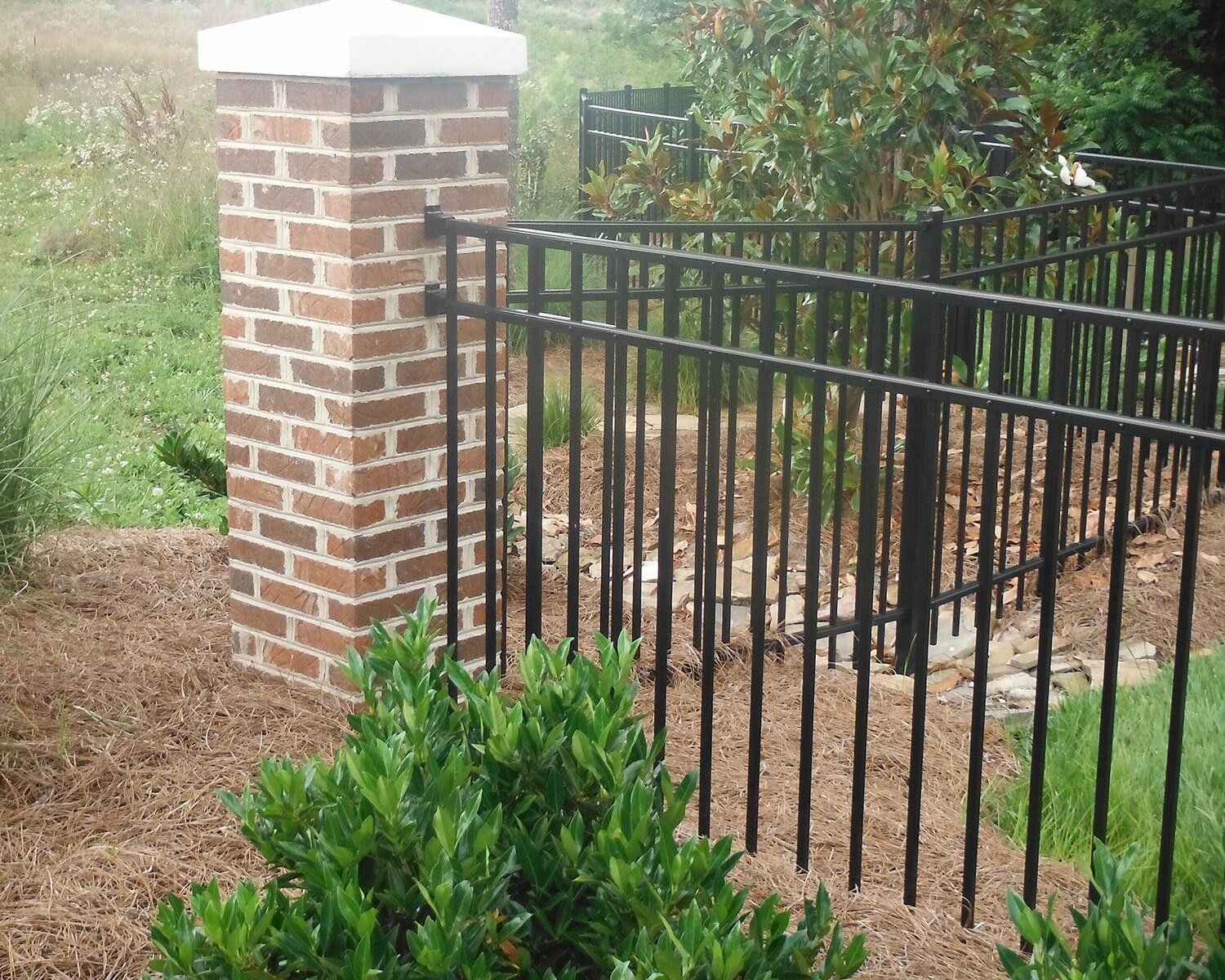 A black fence with a brick pillar in the background