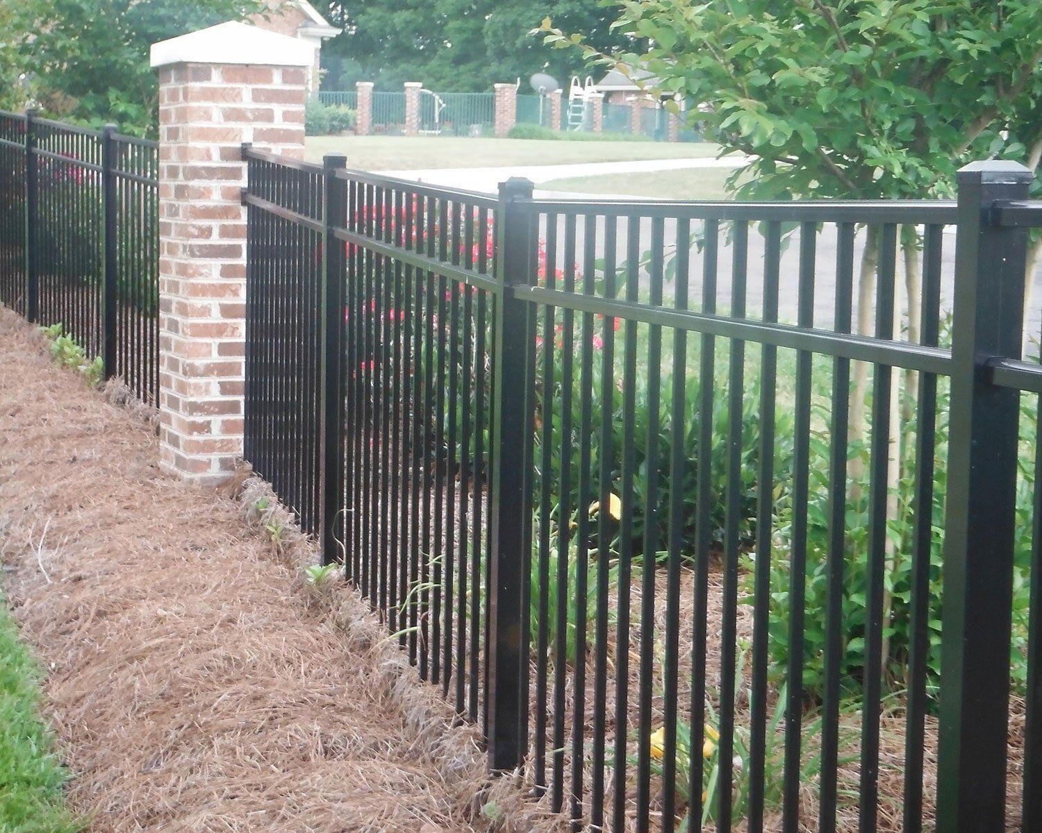 A black fence with a brick post in the background