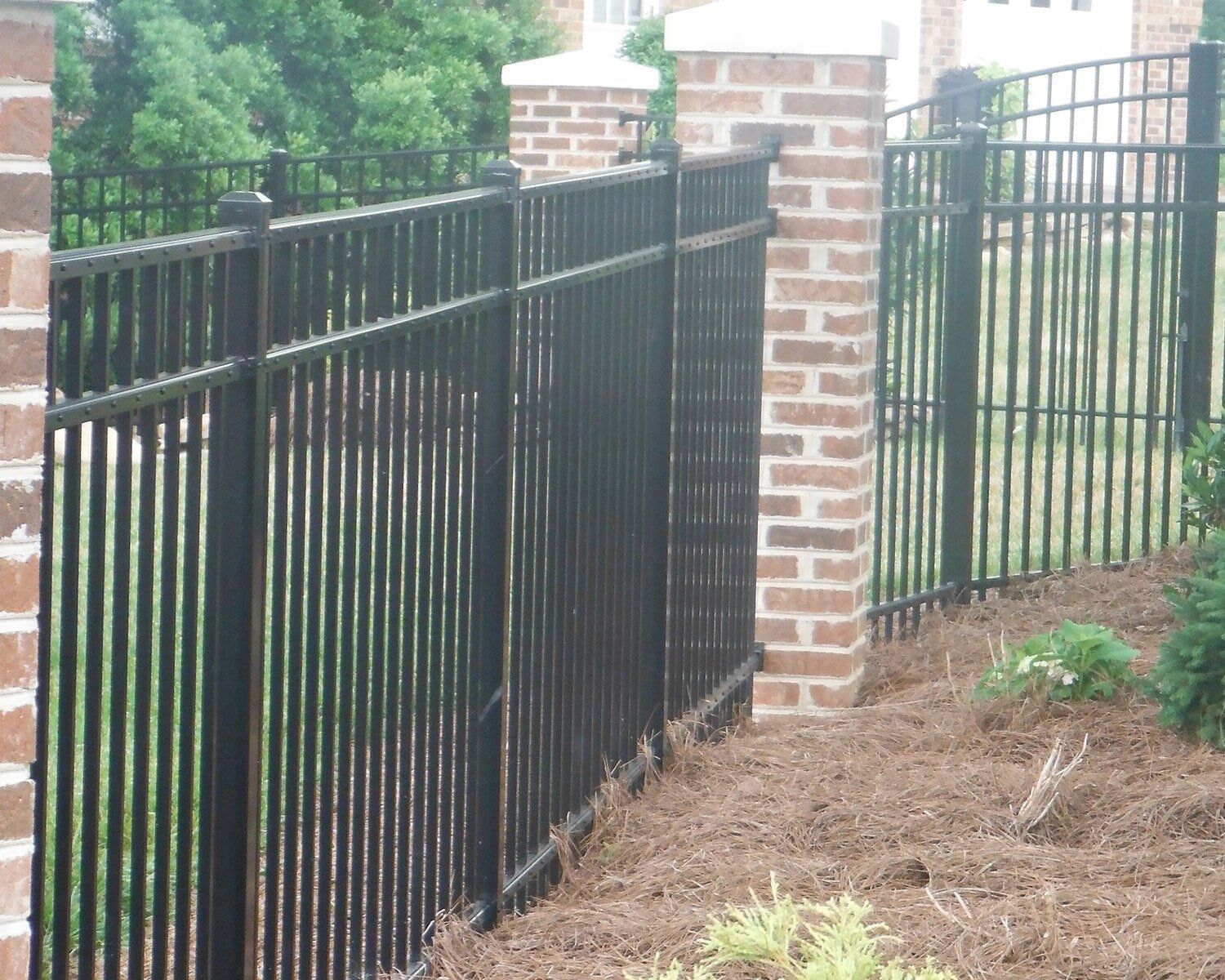 A black fence with a brick pillar in the background
