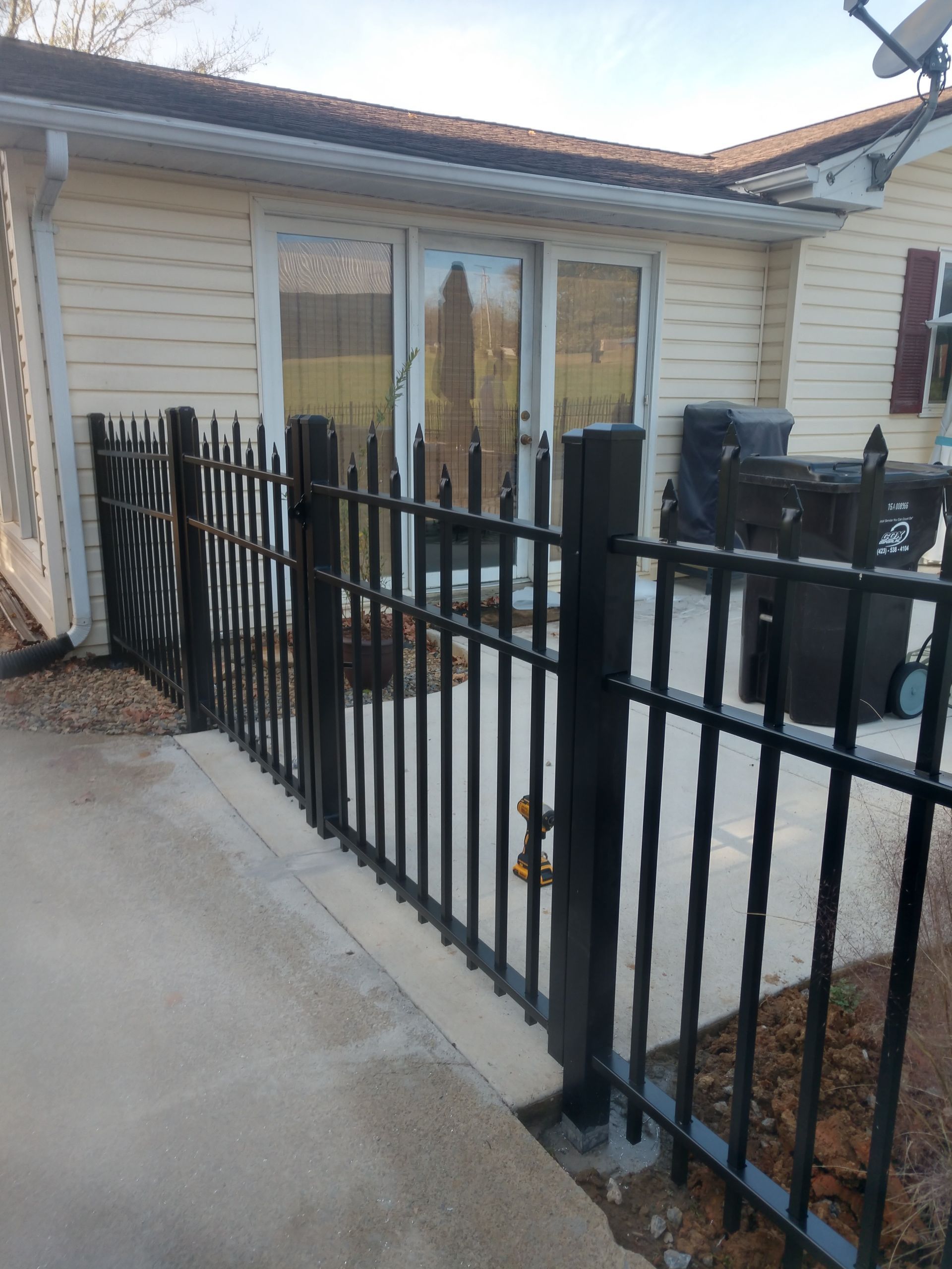 A black fence surrounds a patio area in front of a house.