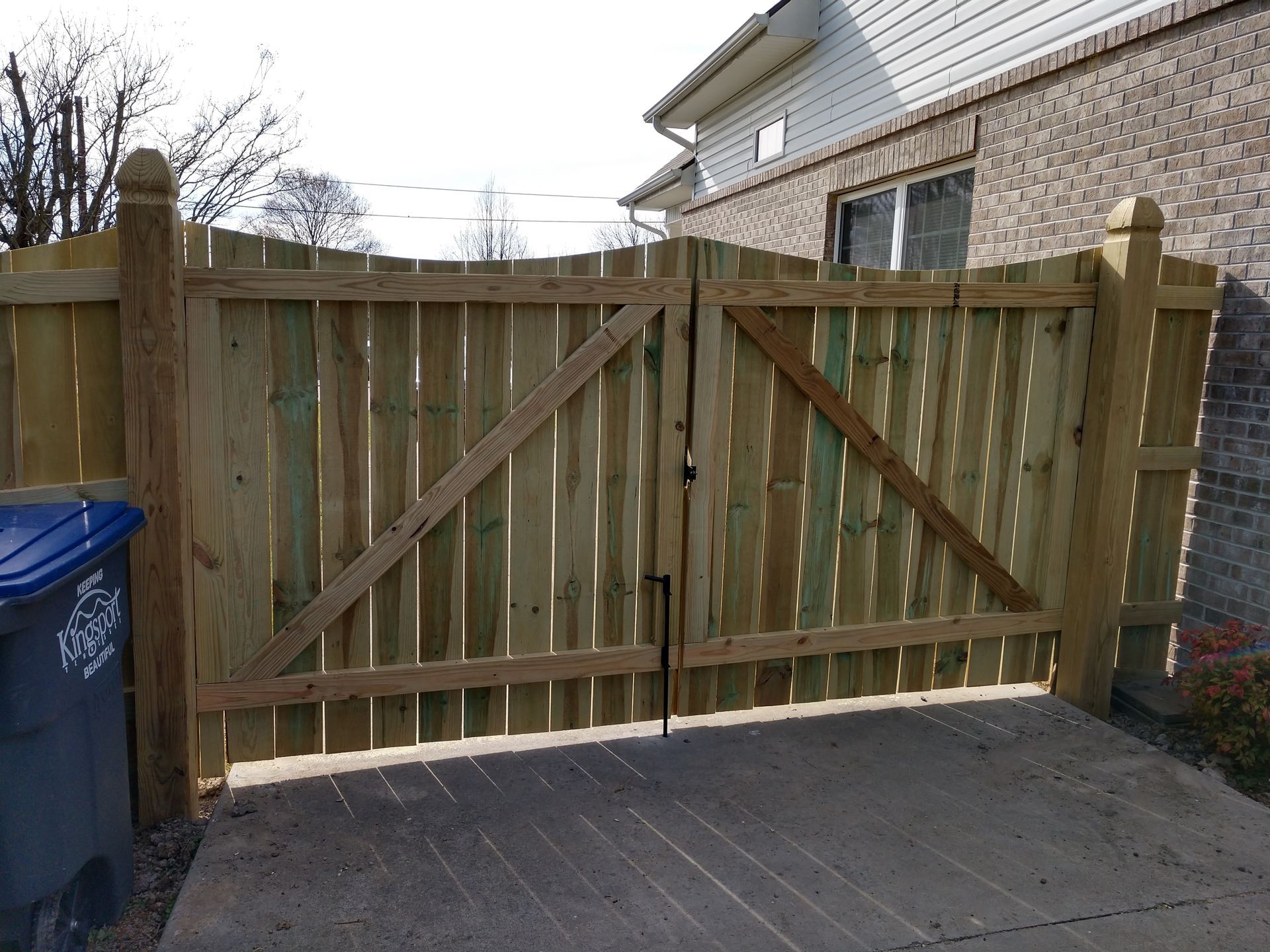 A wooden fence is sitting in front of a brick house.