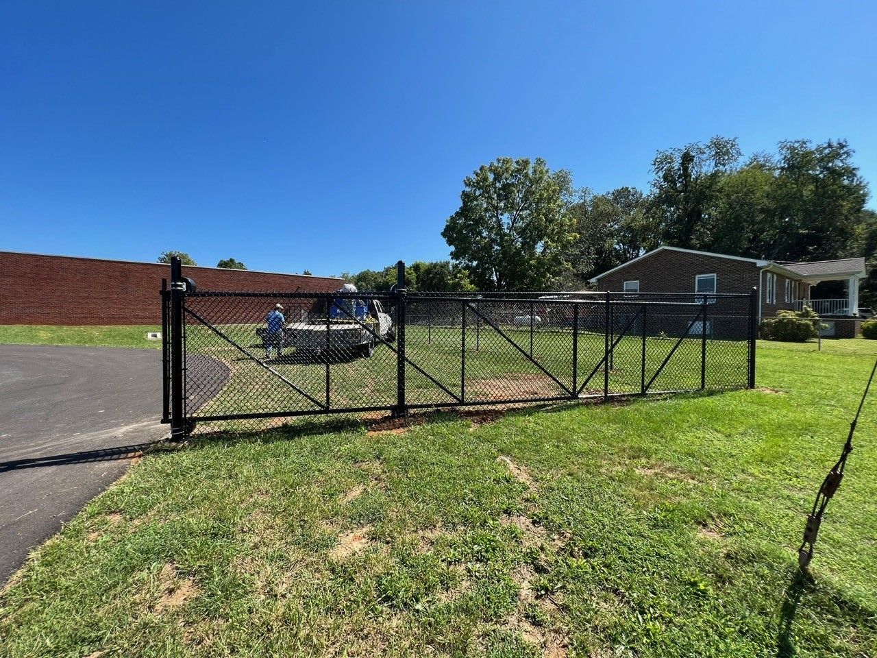 A black chain link fence is surrounding a lush green field.
