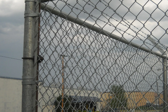 A chain link fence with a cloudy sky in the background