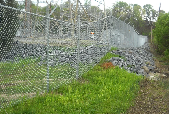 A large building with a fence around it and a sidewalk in front of it.