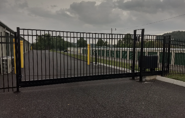 A black metal fence is surrounding a parking lot.