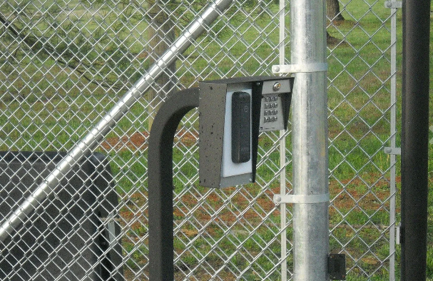 A keypad is attached to a chain link fence.