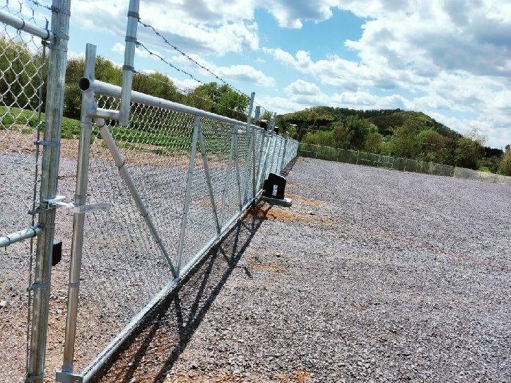 A chain link fence is surrounding a gravel area.