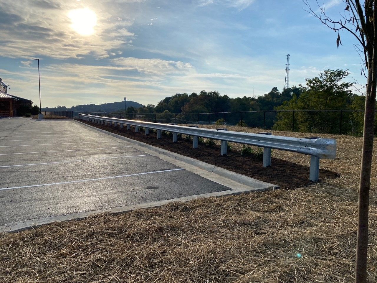 A row of metal barriers along the side of a parking lot.