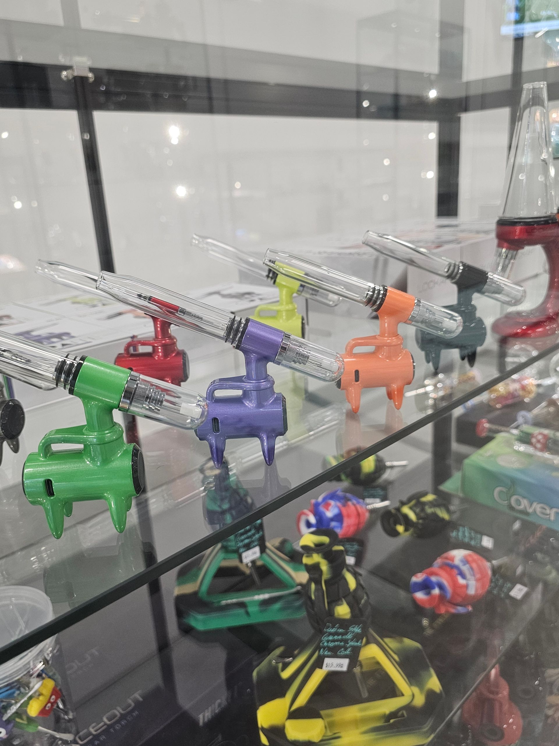 A variety of glass pipes are on display on a glass shelf.