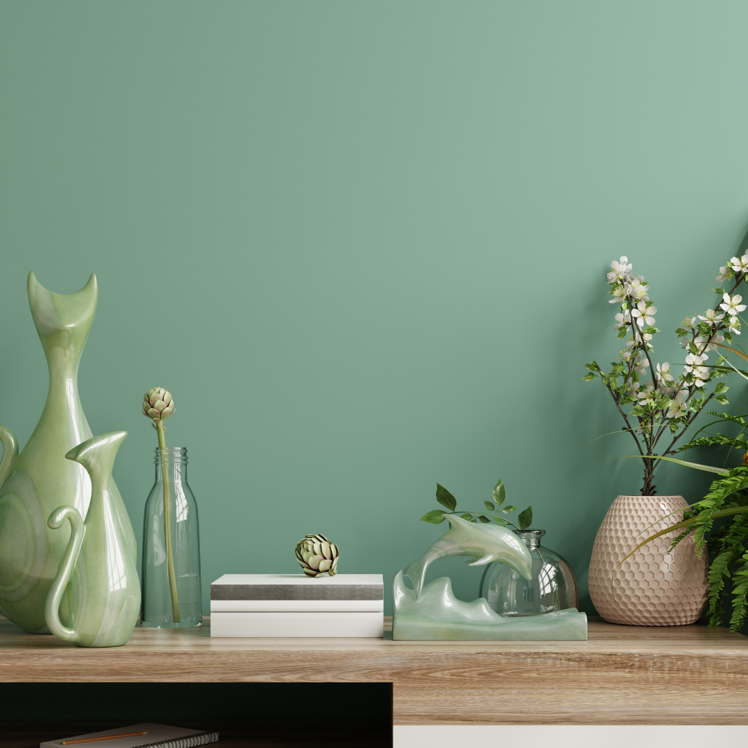 A wooden shelf with vases and flowers on it in front of a green wall.