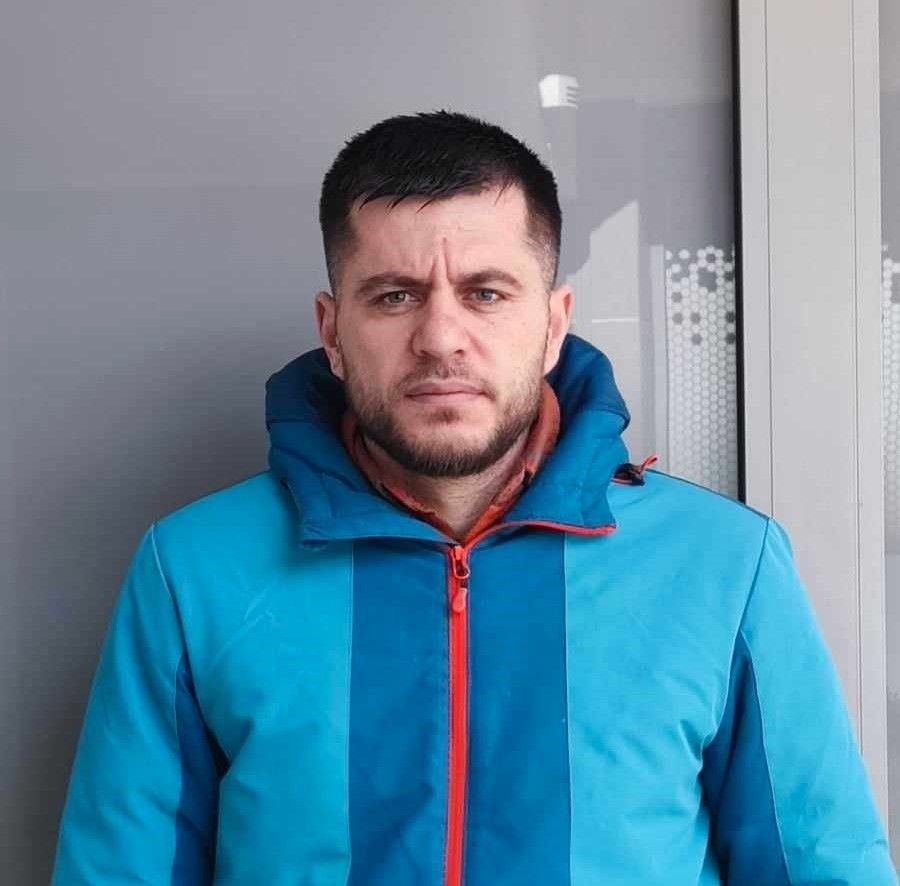 Un plombier est assis dans une salle de bain, tenant une clé et levant le pouce.