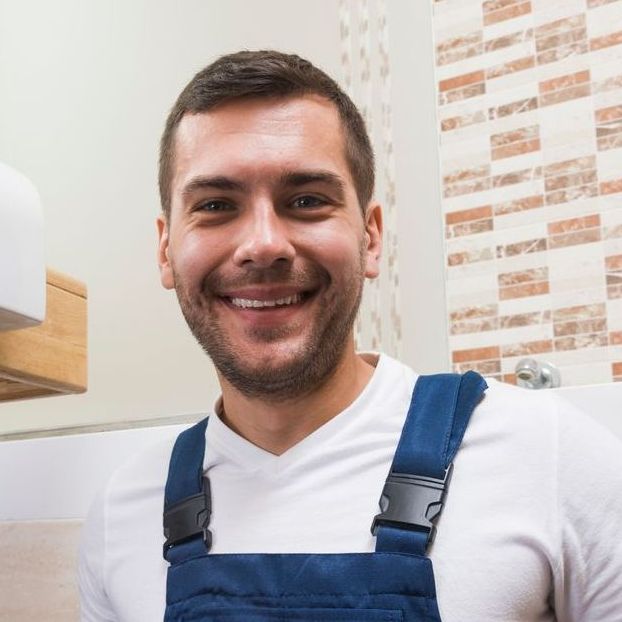 Un homme souriant portant une salopette bleue et une chemise blanche