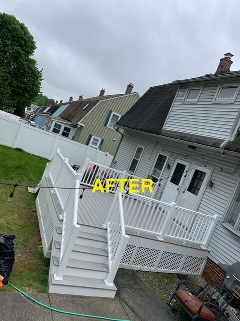 Newly built white deck on the back of a house with lattice and railings. Other houses in the background.