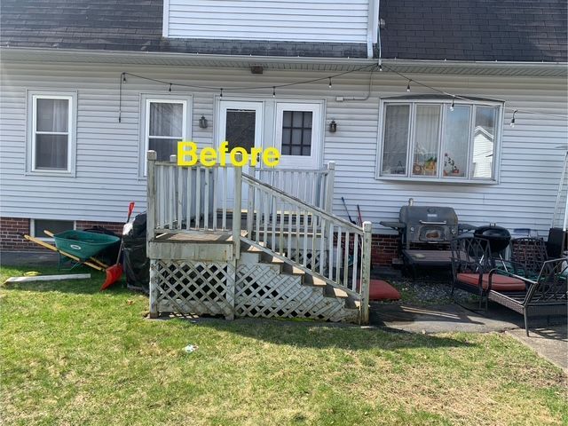 Backyard with gray siding, small deck and stairs, green lawn, 