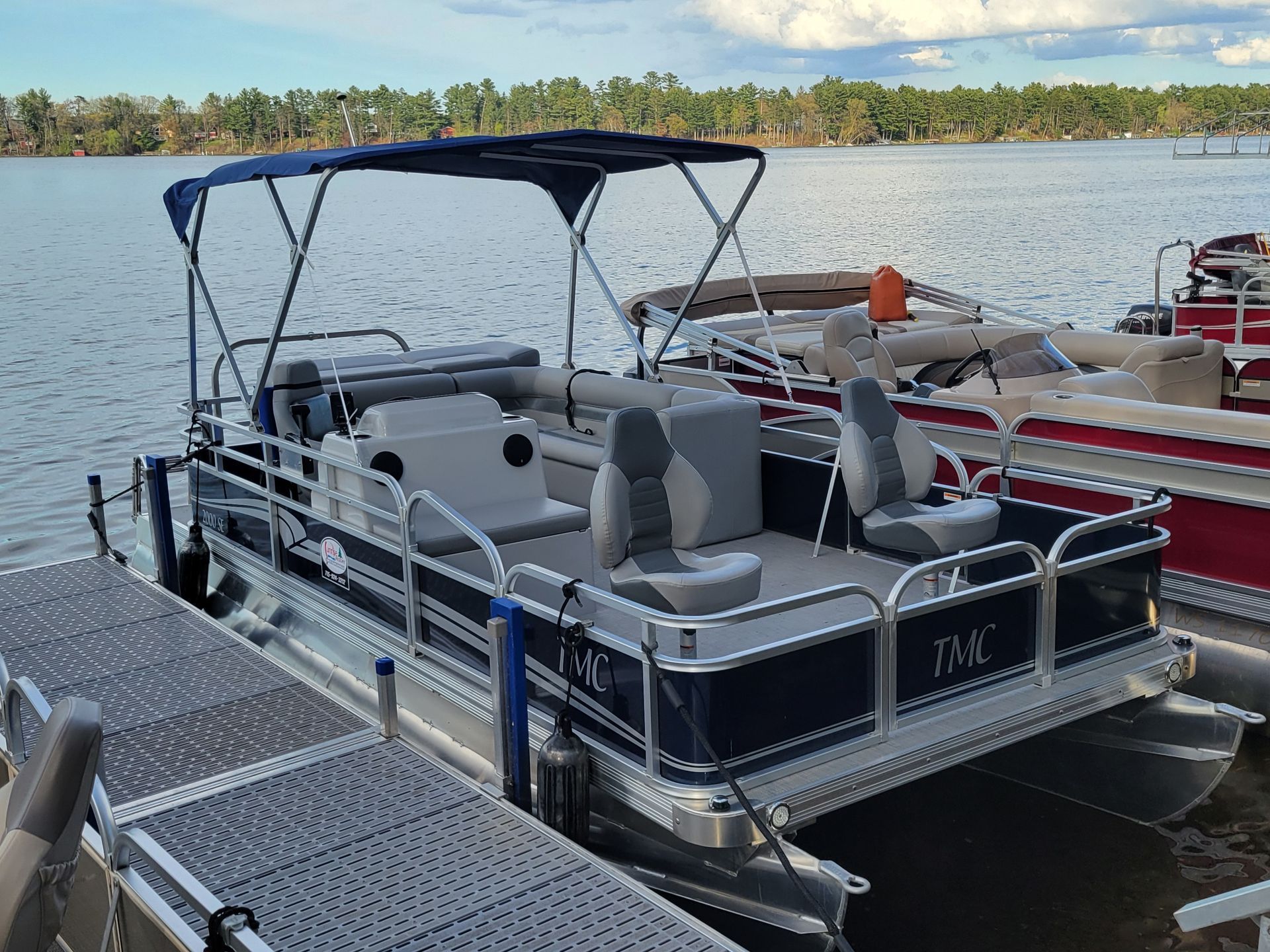 A pontoon boat is docked at a dock on a lake.