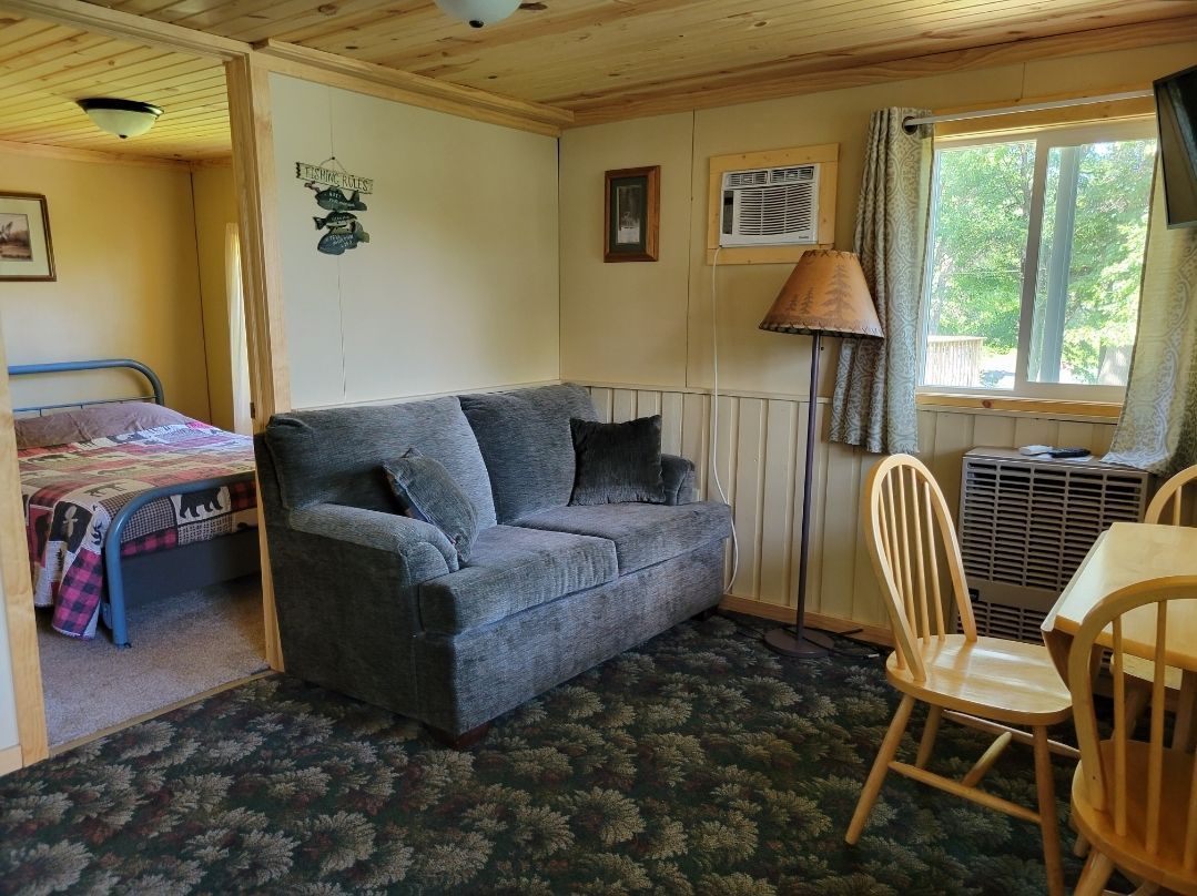 A living room with a couch , chairs , a table and a window.