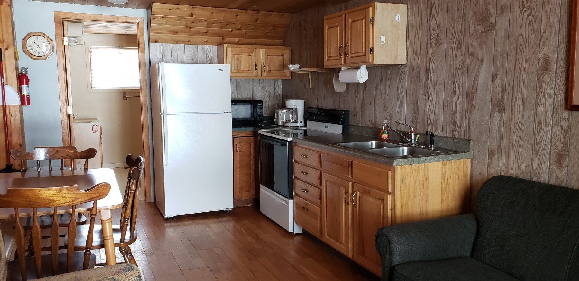 A kitchen with a refrigerator , stove , sink , chair and table.