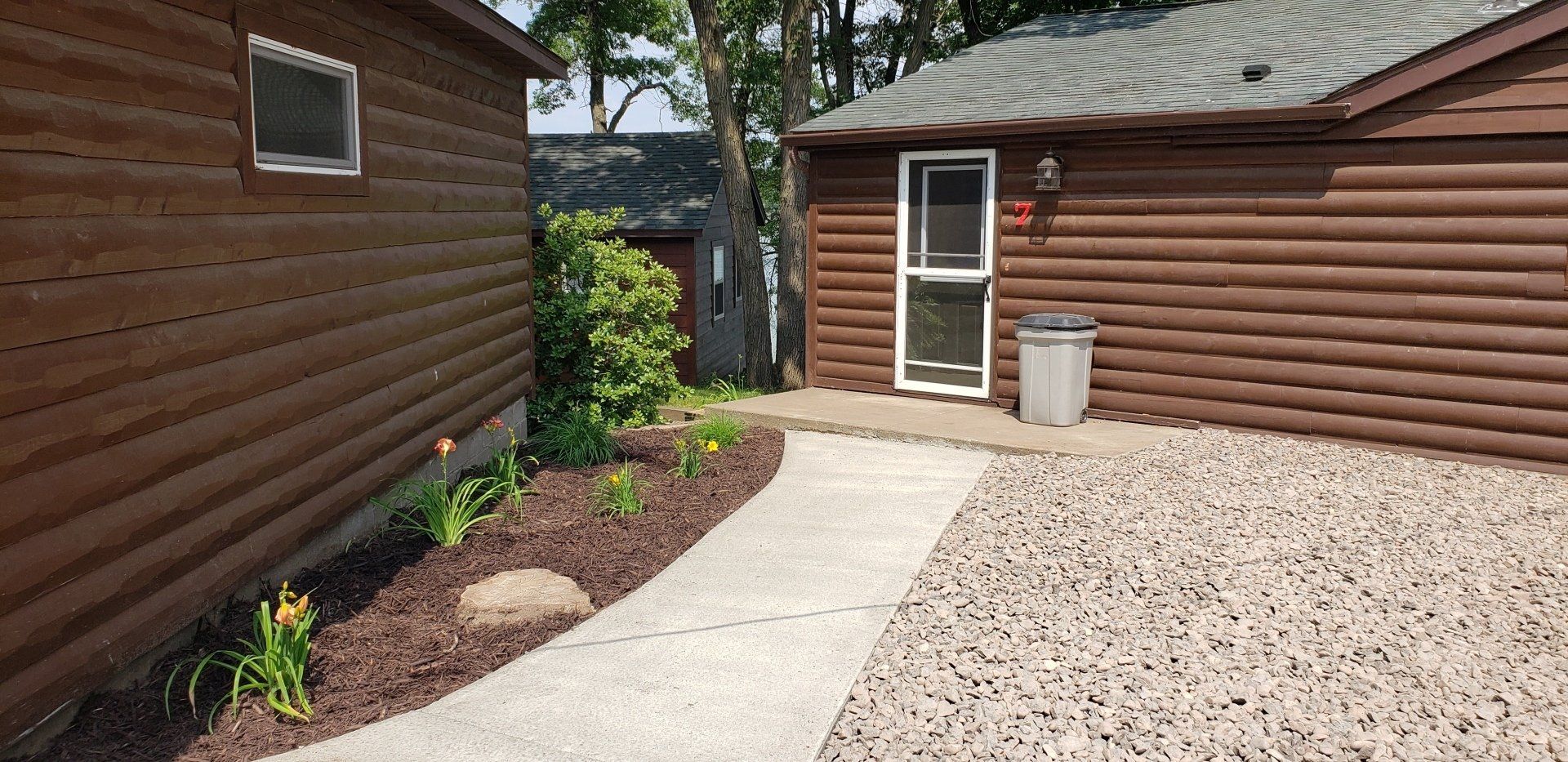 A wooden house with a concrete walkway leading to it.
