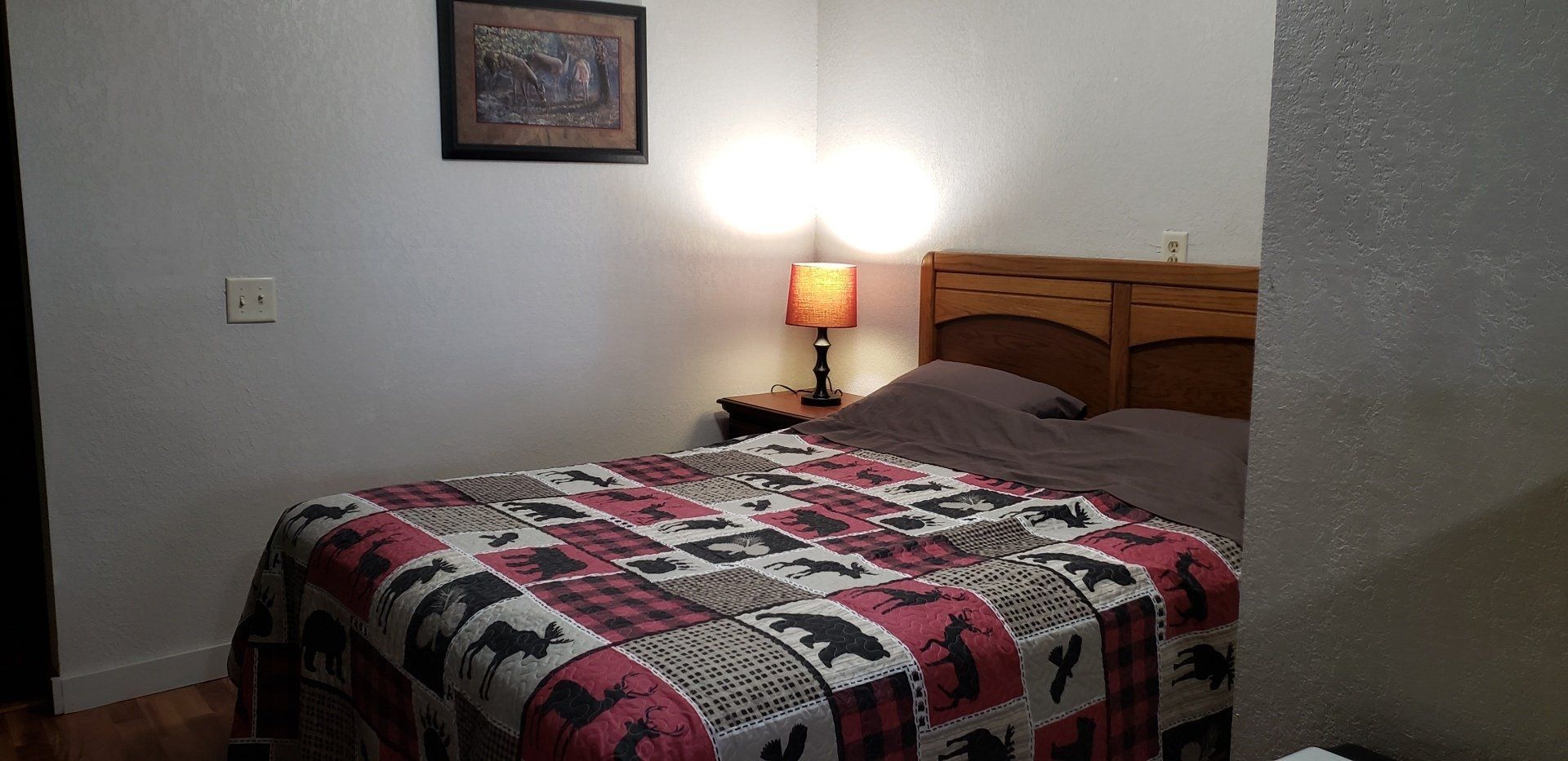 A bedroom with a bed , lamp and picture on the wall.