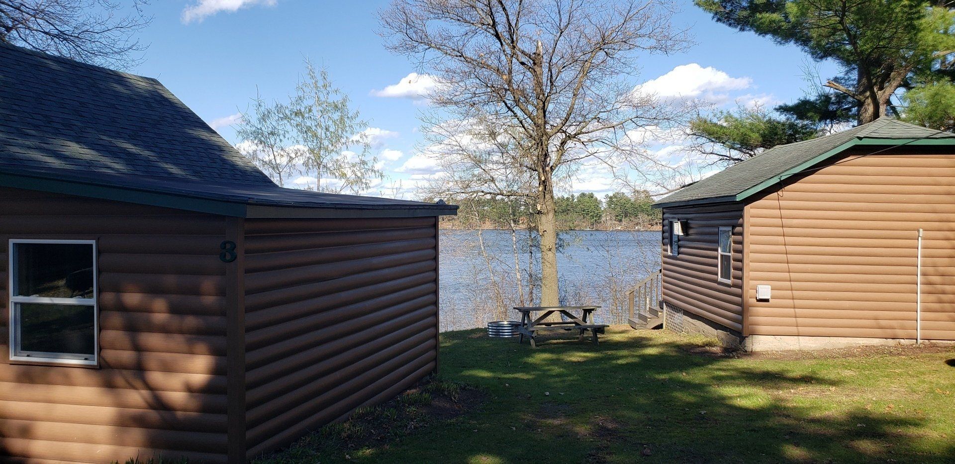 Two log cabins are sitting next to each other on the shore of a lake.